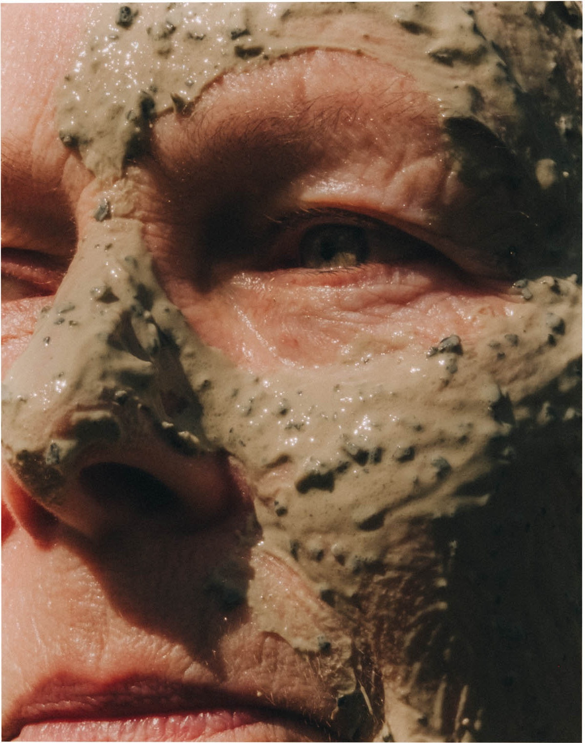 A close-up of a face wearing a seaweed treatment mask in bright sunlight